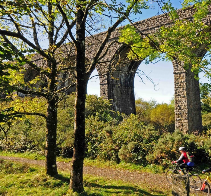 Photo of cyclists on a trail under a viaduct on the Granite Way