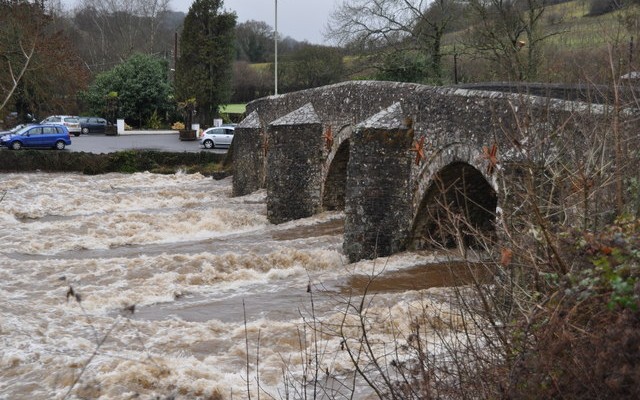 Photo of flood water rushing beneath an old stone bridge at Bickleigh