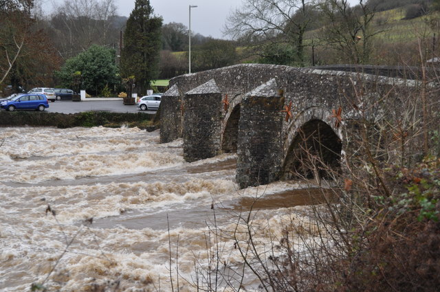 Photo of flood water rushing beneath an old stone bridge at Bickleigh