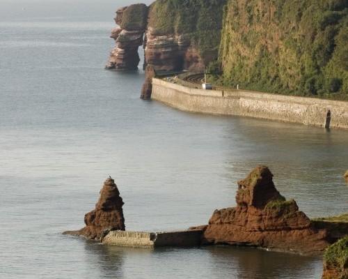 Photo looking along the coast over the sea and red rocks to Parsons tunnel at Dawlish