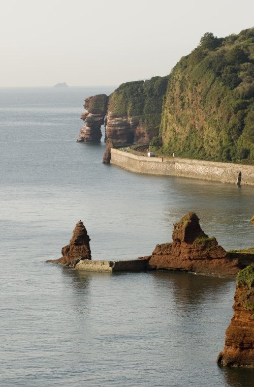 Photo looking along the coast over the sea and red rocks to Parsons tunnel at Dawlish