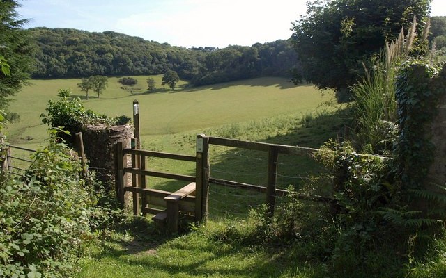 Photo of a stile in front of fields and woodland