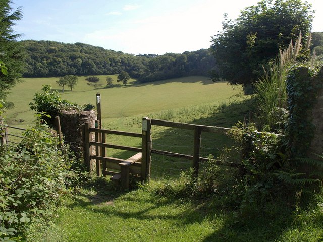 Photo of a stile in front of fields and woodland