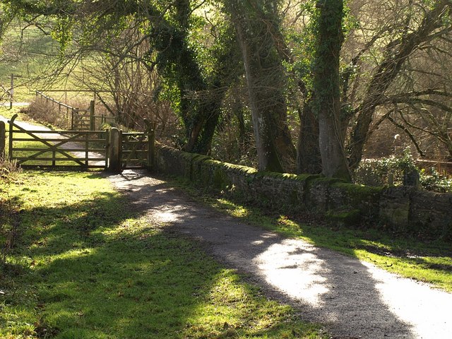 Photo of a quiet lane alongside a stone wall to a footpath gate