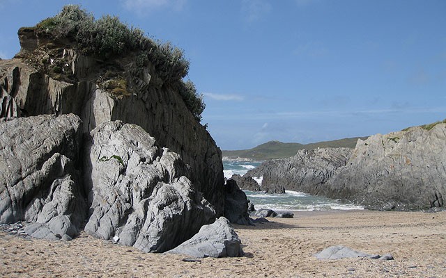 Photo looking across sand and through rocks to the sea at Barricane beach