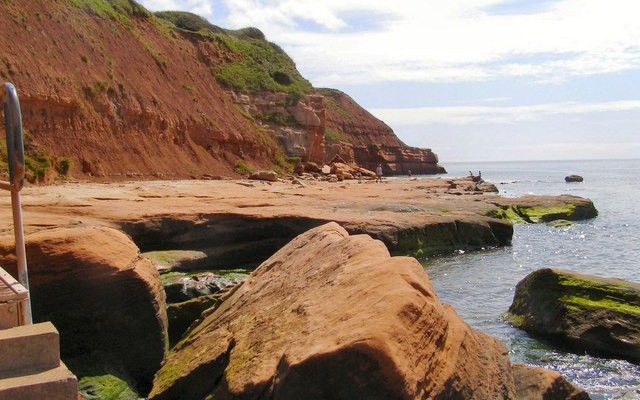 Photo of the red sandstone shore and sea with cliffs behind near Orcombe Point in Exmouth