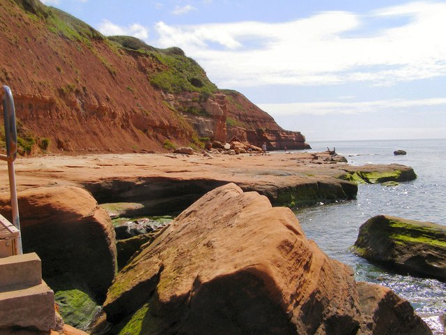 Photo of the red sandstone shore and sea with cliffs behind near Orcombe Point in Exmouth