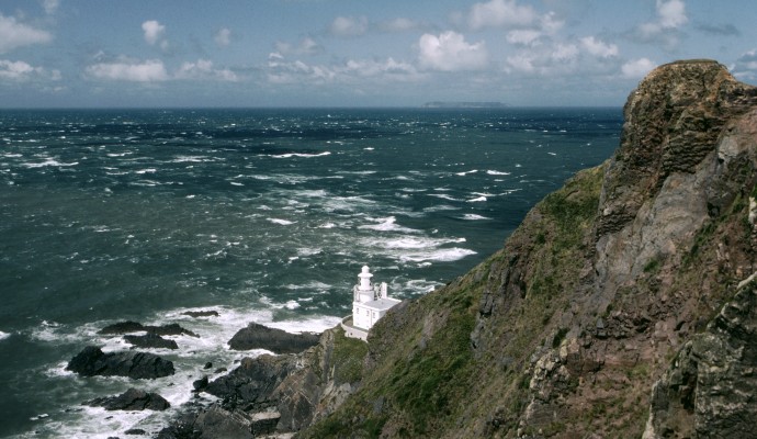 Photo of the light house at Hartland point in north Devon, looking down the cliffs to the lighthouse and out over a rough sea towards Lundy