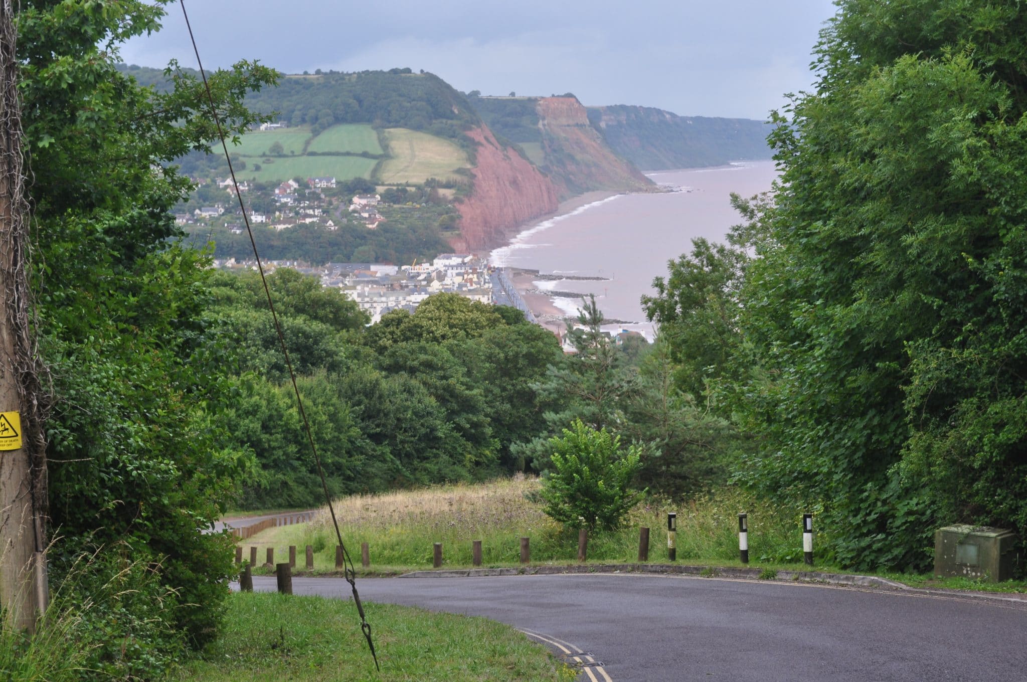 Photo looking down into Sidmouth from Peak Hill with the town in the bottom of the valley and the sea and red cliffs in the background