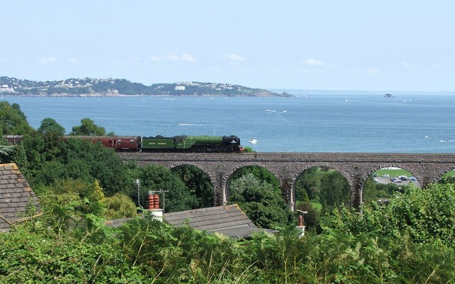 Photo of Broadsands viaduct with a train crossing it and the sea and coastline in the background