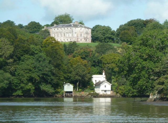 Photo looking across the river Dart to the boathouse at Sharpham House with the main house on the hill behind