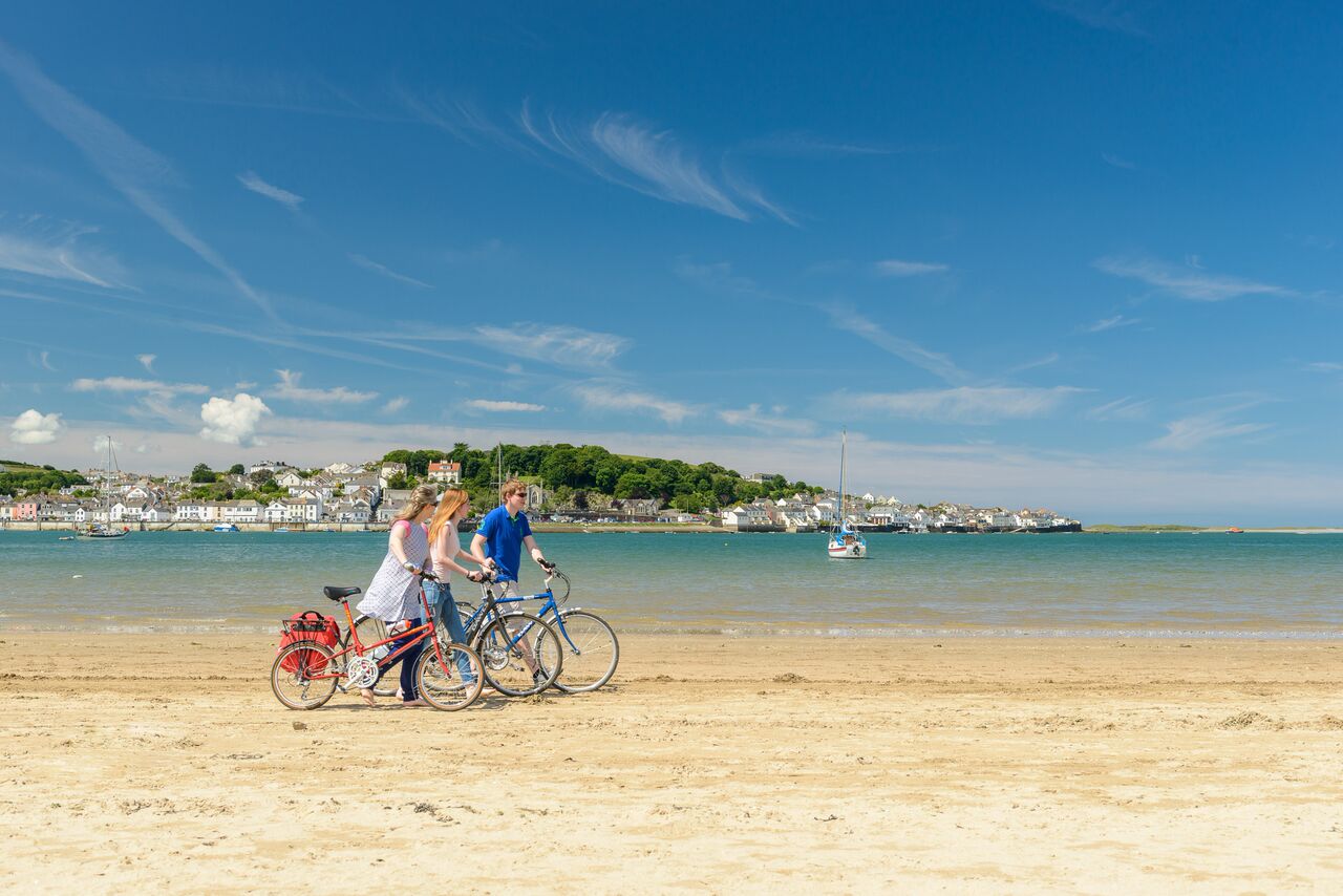 Photo of people pushing bicycles along the beach at Instow