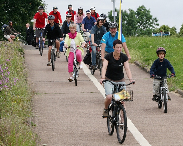 Photo of a group of adults and children cycling along a cycle path