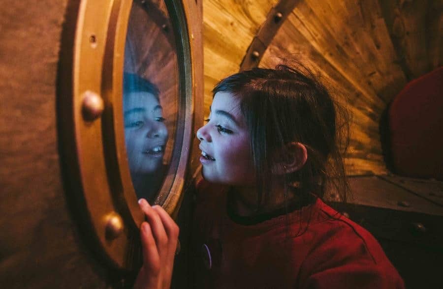 Photo of a girl looking through a portal window in the Seaton Jurassic time machine