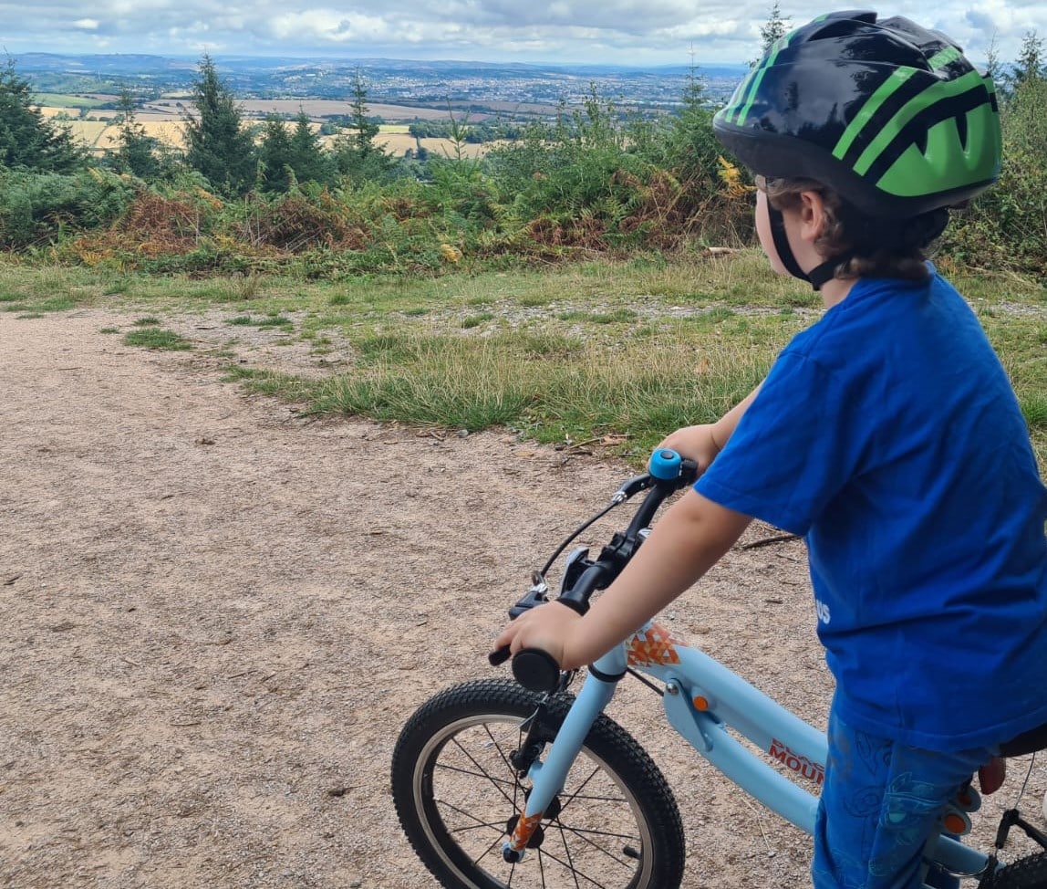 Small boy on bike looking out from Haldon woods